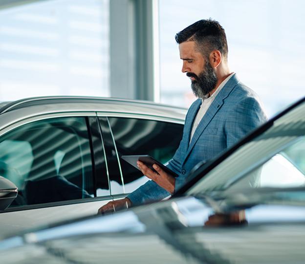 man looking at tablet next to car